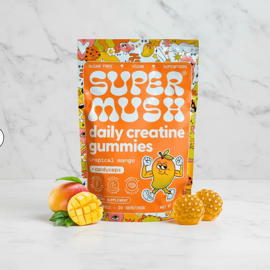 A busy professional athlete grabbing three mango-flavored creatine gummies from a compact bottle during a quick morning ro...