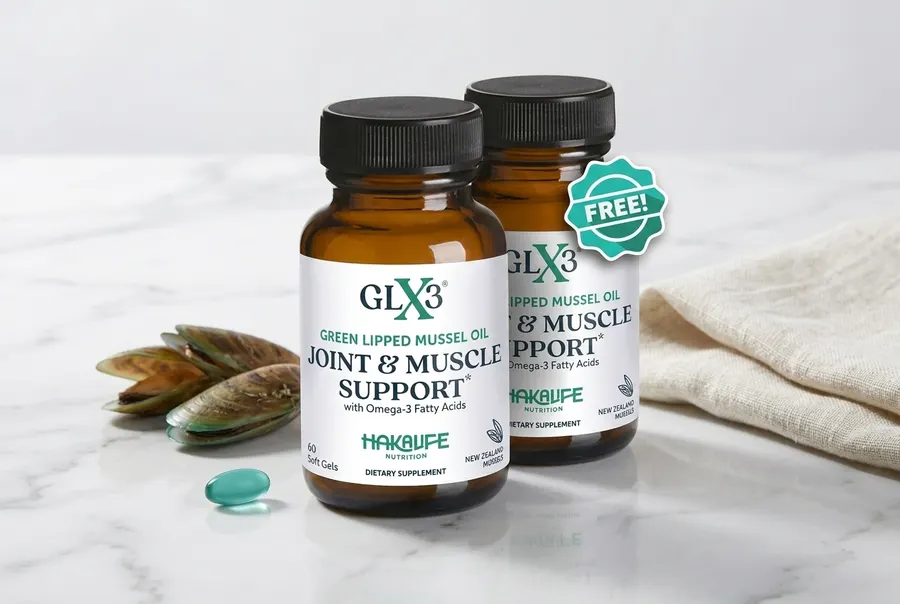A frosted glass bottle of green-lipped mussel oil softgels sits upright on a smooth stone surface beside a small ceramic d...