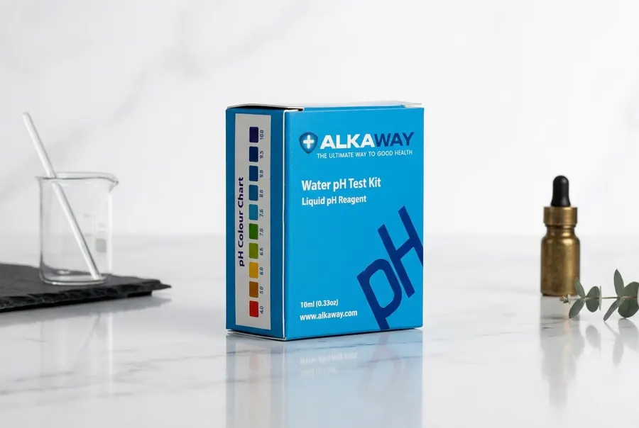 A slim frosted dropper bottle of pH test solution sitting upright on a clean bathroom counter next to a small clear glass ...