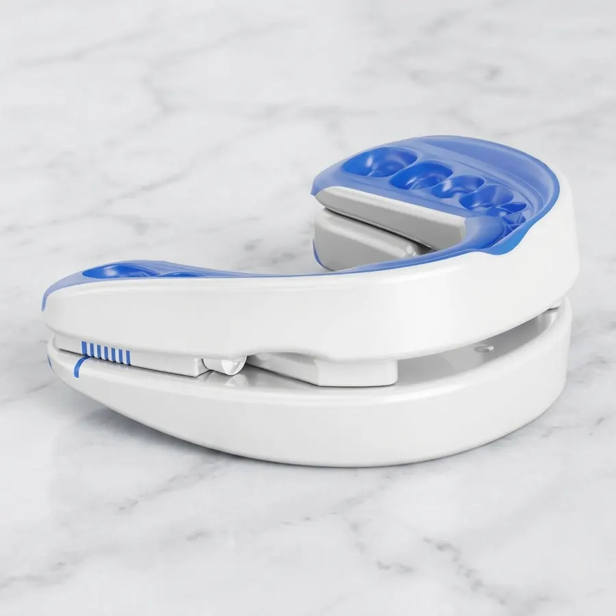 A man in his 40s holding an adjustable anti-snoring mouthpiece with visible micro-adjustment dial mechanism, turning the d...