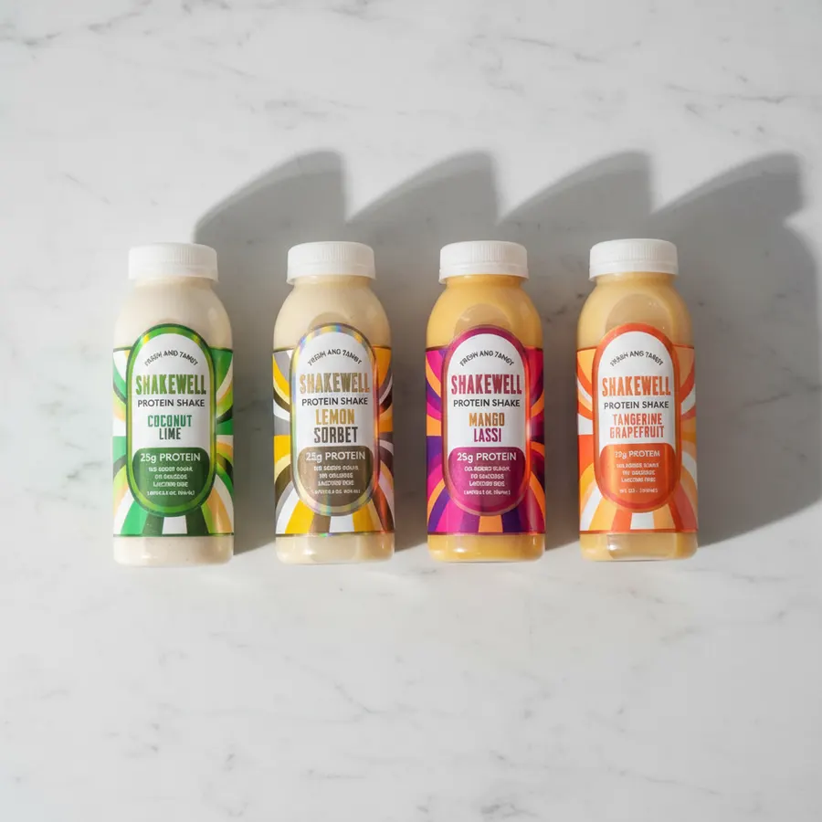 A busy parent or professional mid-morning, seated with an open bottle of fresh liquid whey protein shake on the desk or ki...