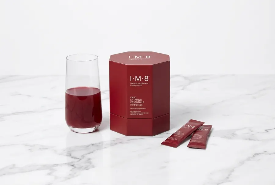 A simple frosted glass of daily supplement powder drink on white marble countertop, one small succulent plant beside it, b...