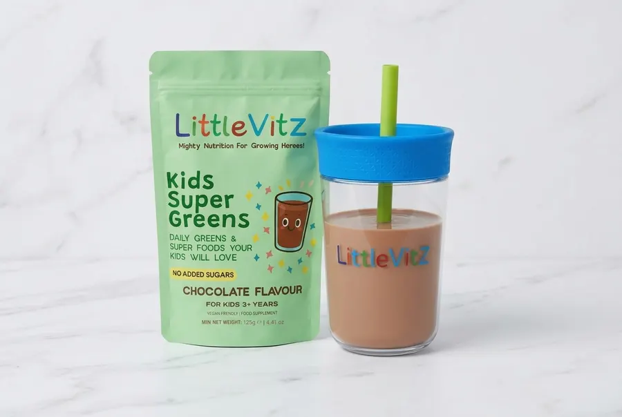 A matte pouch of children's greens supplement standing upright on a bright white kitchen counter, centered composition, oc...
