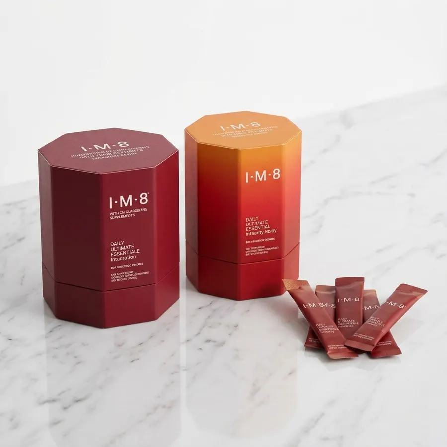 A single premium matte sachet of daily supplement powder beside a minimalist glass of water on a clean white marble counte...