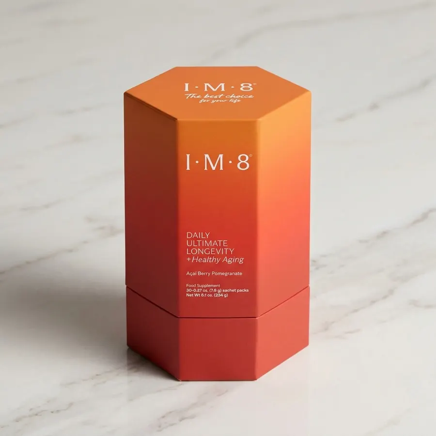 A frosted glass jar of longevity supplement powder on a clean marble counter beside a measuring scoop, warm morning light ...