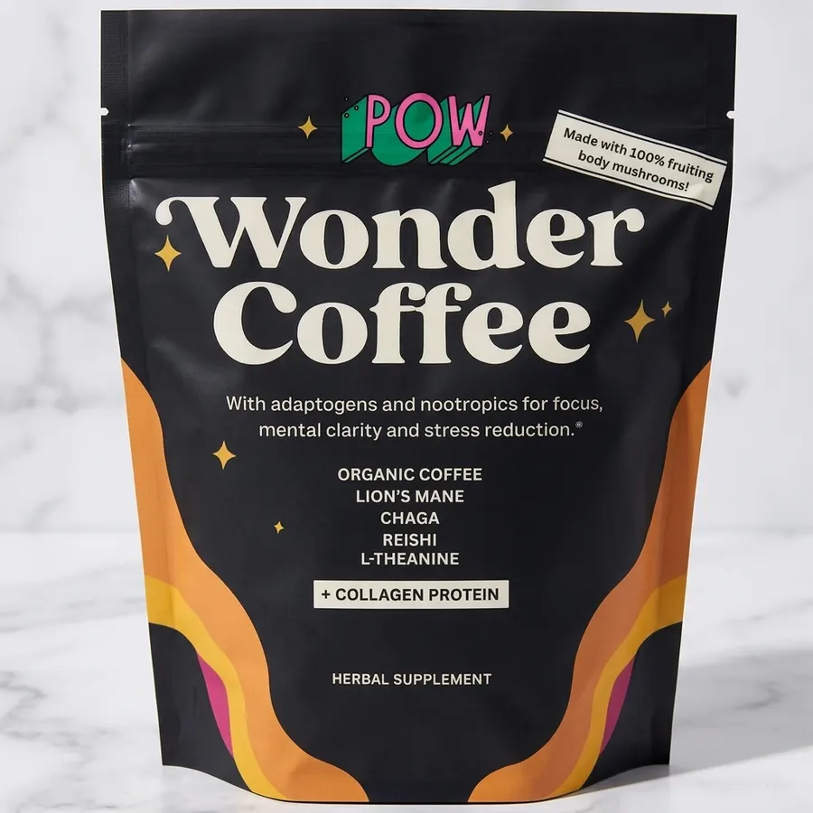 A single-serving pouch of functional coffee blend on a marble bathroom counter next to a glass of water and a small potted...