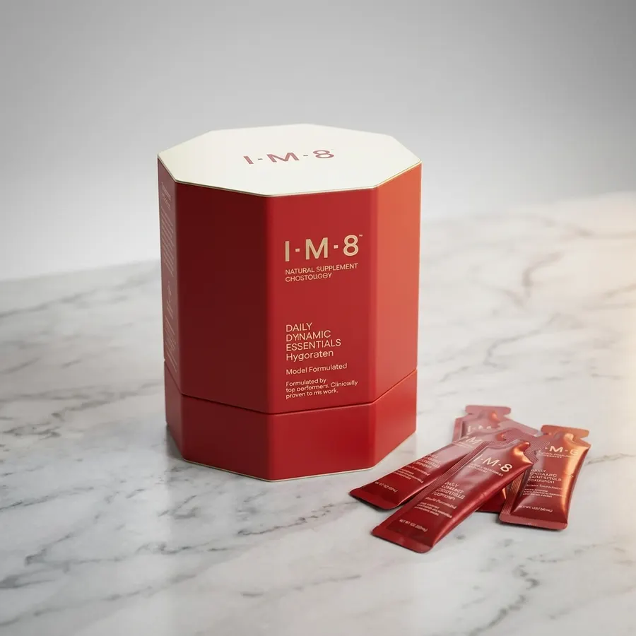 A single white sachet of daily supplement powder next to a clear glass of water on a marble kitchen counter, top-down view...