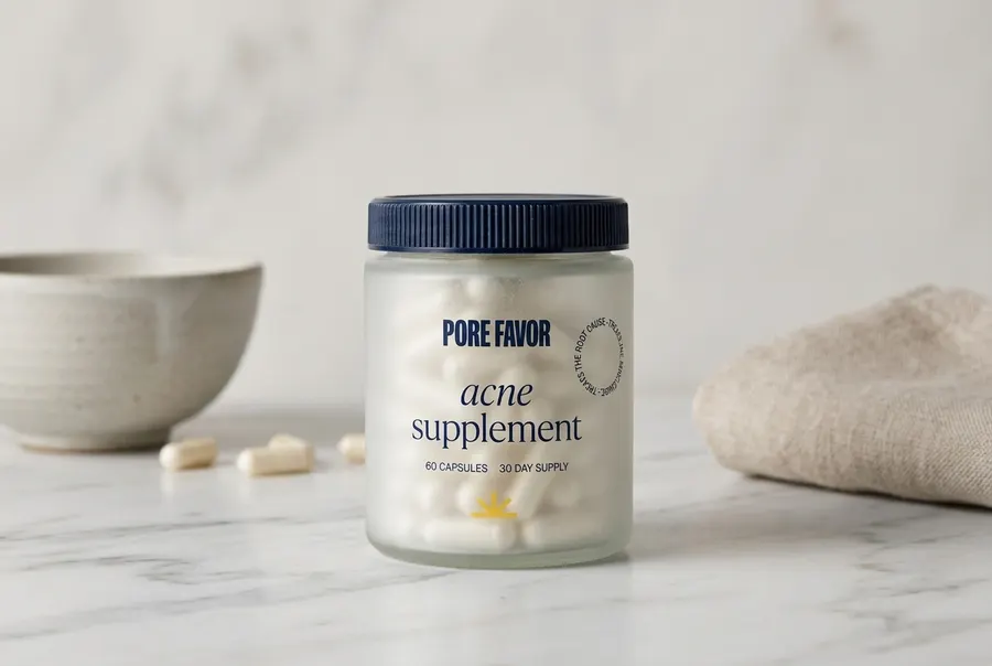 A matte black supplement bottle with a frosted label sits upright on a clean marble kitchen counter next to a small white ...