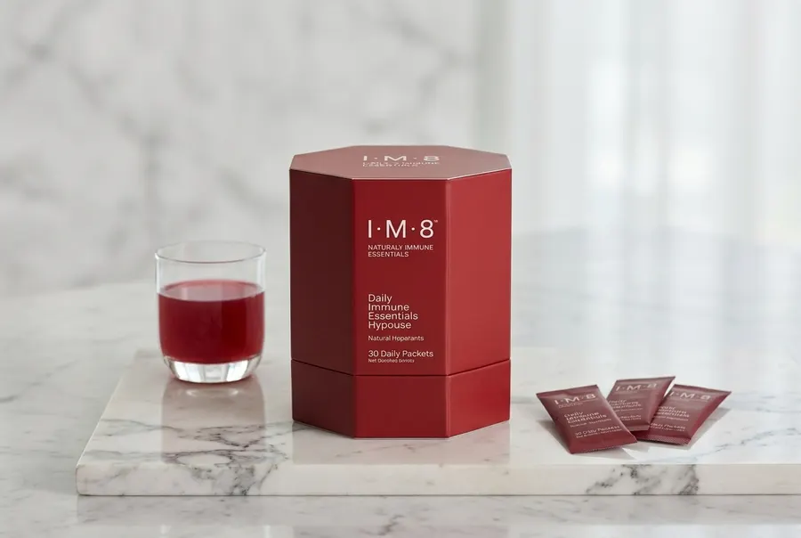 A single-serve pouch of comprehensive daily supplement powder centered upright occupying 60% of frame height, sitting on a...