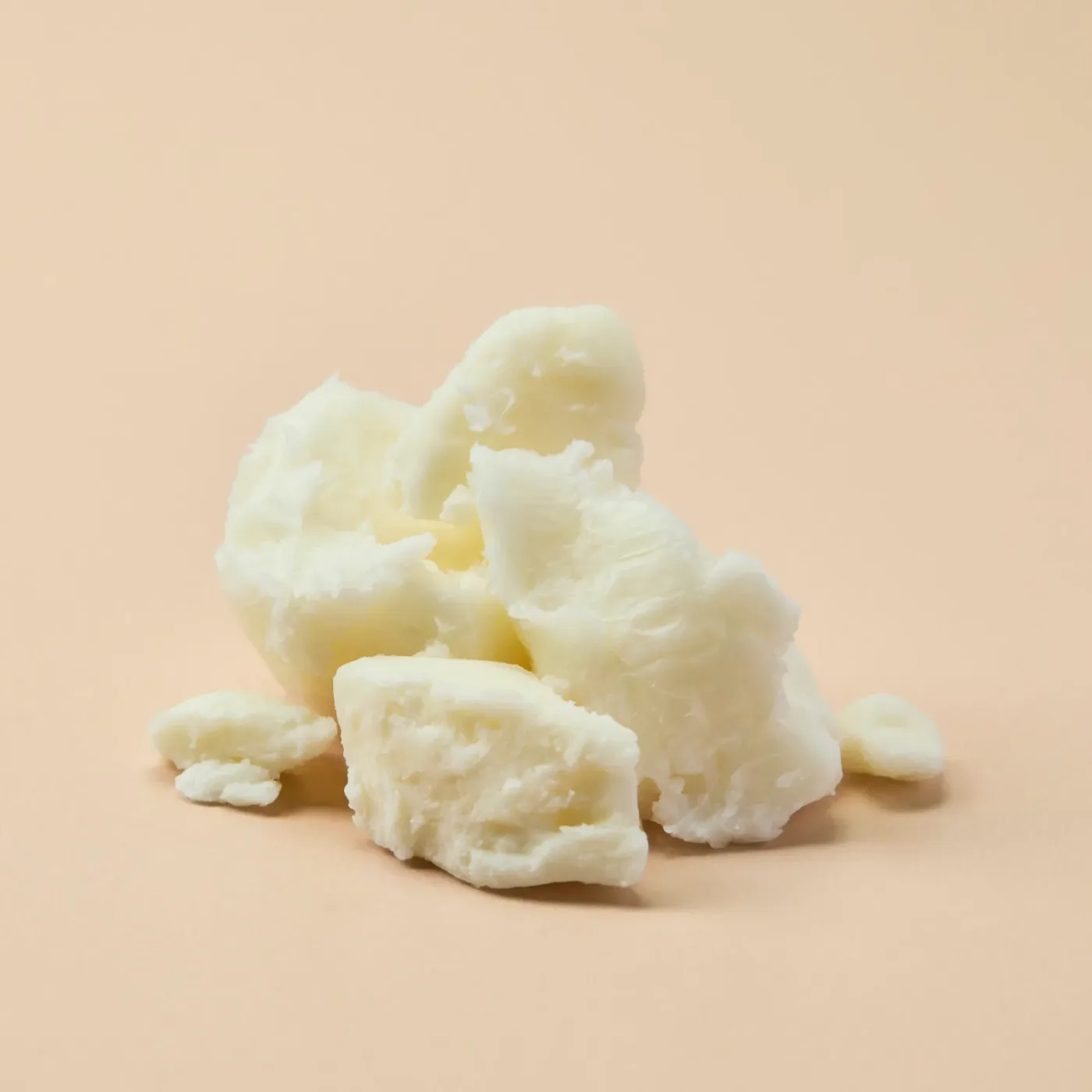 A frosted glass jar of ultra-refined white shea butter sits centered on a light wood surface with generous vertical cleara...